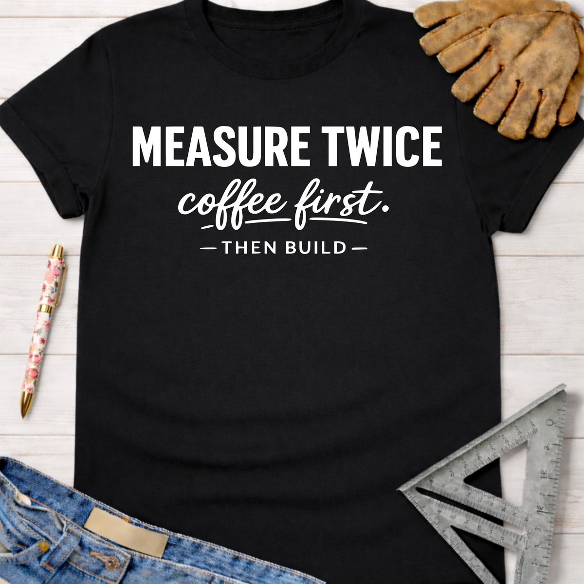 Women's funny woodworking graphic tee shirt for female woodworkers, makers, and DIY builders — Sawdust & Ponytails. Black cotton tee with "MEASURE TWICE coffee first. — THEN BUILD —" in white text, beside a work glove and ruler.