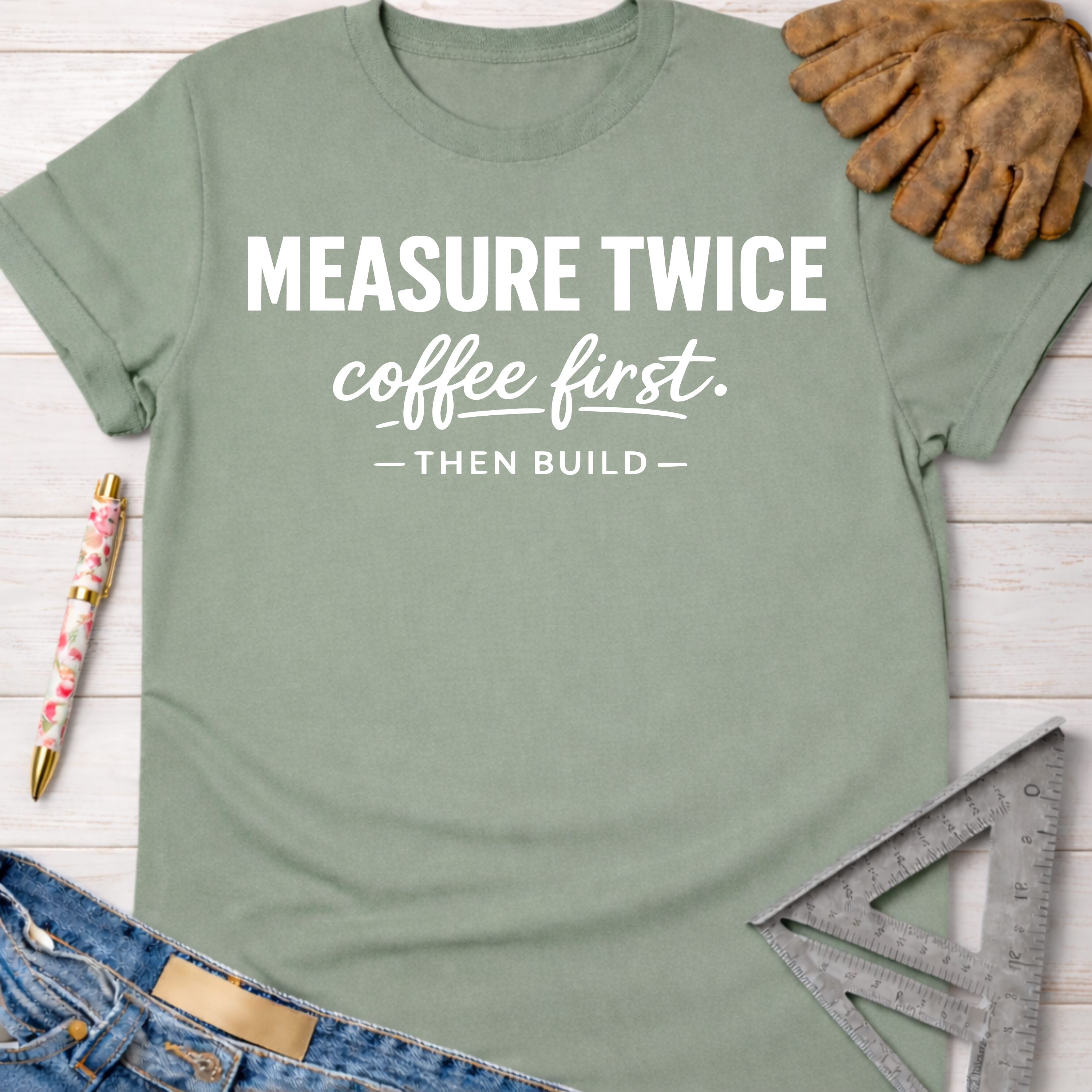 Women's funny woodworking graphic tee shirt for female woodworkers, makers, and DIY builders — Sawdust & Ponytails. Sage green cotton tee with "MEASURE TWICE coffee first. — THEN BUILD —" in white text.