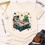 Cream cotton t-shirt with a graphic of an astronaut and alien woodworking at a table saw.