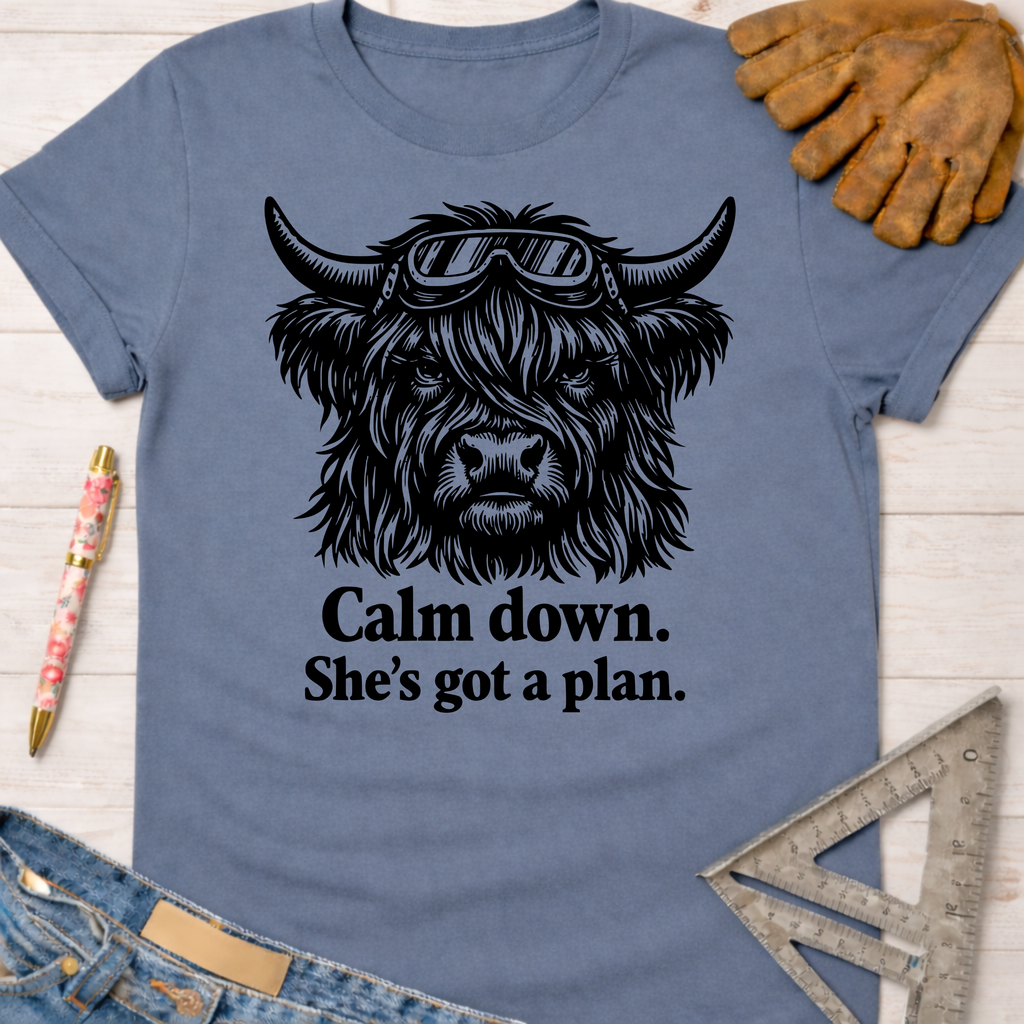 Women's funny woodworking graphic tee shirt for female woodworkers, makers, and DIY builders — Sawdust & Ponytails. Blue t-shirt with a black graphic of a Highland cow wearing goggles and the text "Calm down. She's got a plan.