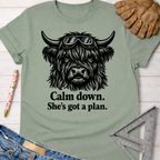 Women's funny woodworking graphic tee shirt for female woodworkers, makers, and DIY builders — Sawdust & Ponytails. Sage green t-shirt with a black graphic of a shaggy cow wearing goggles and the text "Calm down. She's got a plan.