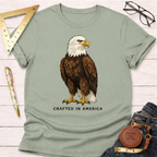 Sage green 100% cotton t-shirt with a detailed bald eagle graphic and "CRAFTED IN AMERICA" text.