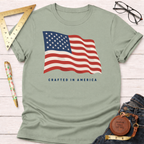 Sage green t-shirt with a waving American flag graphic and "CRAFTED IN AMERICA" text.