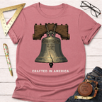 Heather rose t-shirt with a detailed Liberty Bell graphic and "CRAFTED IN AMERICA" text.