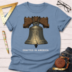 Light blue cotton t-shirt with a detailed Liberty Bell graphic and "CRAFTED IN AMERICA" text.