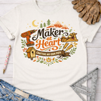 Women's funny woodworking graphic tee shirt for female woodworkers, makers, and DIY builders — Sawdust & Ponytails. Cream t-shirt with "Maker at Heart: Crafting My Own Path" graphic, featuring tools, mountains, and a birdhouse.