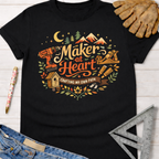 Women's funny woodworking graphic tee shirt for female woodworkers, makers, and DIY builders — Sawdust & Ponytails. Black cotton tee with "Maker at Heart, Crafting My Own Path" graphic featuring tools, mountains, and a moon.