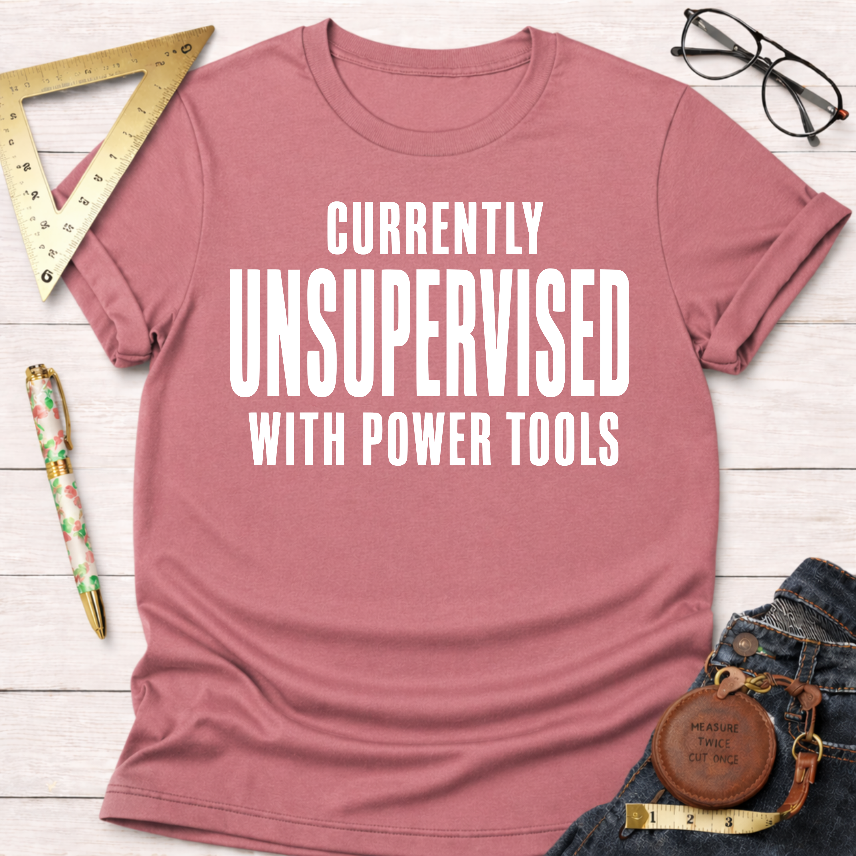 Women's funny woodworking graphic tee shirt for female woodworkers, makers, and DIY builders — Sawdust & Ponytails. Pink cotton t-shirt with "CURRENTLY UNSUPERVISED WITH POWER TOOLS" in white text.