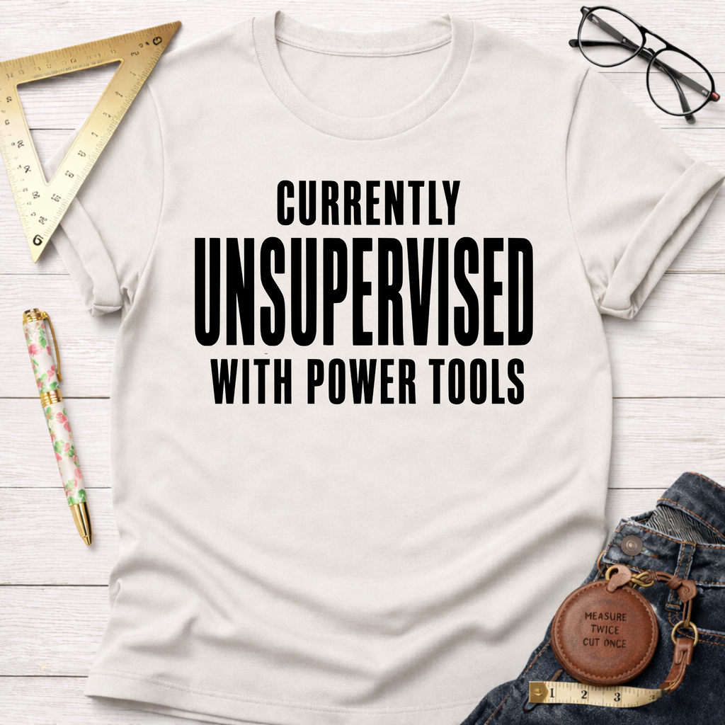 Women's funny woodworking graphic tee shirt for female woodworkers, makers, and DIY builders — Sawdust & Ponytails. Cream t-shirt with "CURRENTLY UNSUPERVISED WITH POWER TOOLS" in black text.