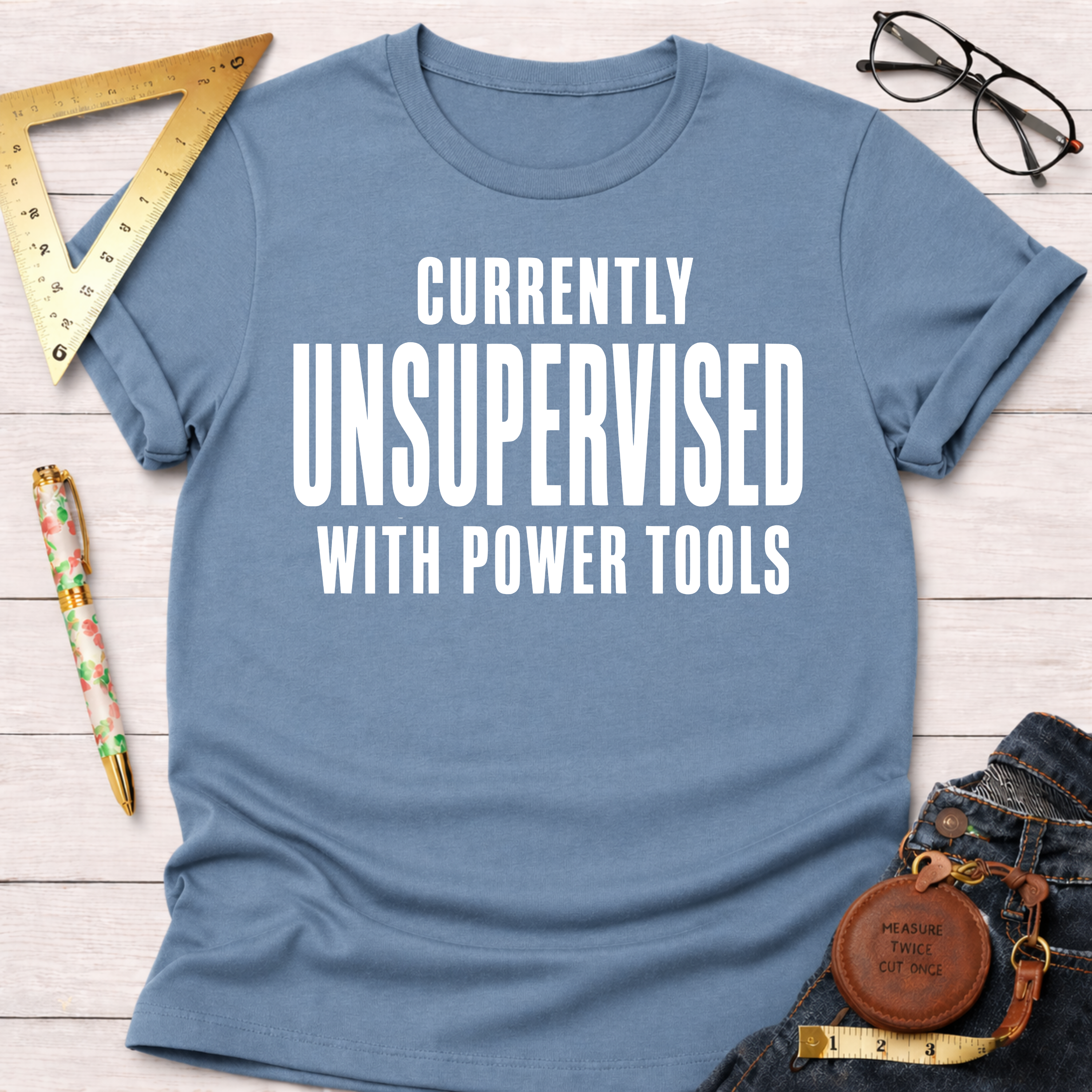 Women's funny woodworking graphic tee shirt for female woodworkers, makers, and DIY builders — Sawdust & Ponytails. Light blue cotton t-shirt with "CURRENTLY UNSUPERVISED WITH POWER TOOLS" in white text.