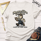 Women's funny woodworking graphic tee shirt for female woodworkers, makers, and DIY builders — Sawdust & Ponytails. Cream t-shirt with a bear carrying wood and "Measure Twice Cut Once Curse. Buy More Wood" text.