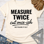 Women's funny woodworking graphic tee shirt for female woodworkers, makers, and DIY builders — Sawdust & Ponytails. Cream t-shirt with "MEASURE TWICE cut once-ish WE FIGURE IT OUT" in black text.