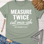 Women's funny woodworking graphic tee shirt for female woodworkers, makers, and DIY builders — Sawdust & Ponytails. Sage green cotton tee with "MEASURE TWICE cut once-ish WE FIGURE IT OUT" text.