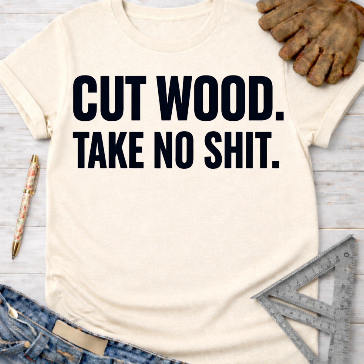 Women's funny woodworking graphic tee shirt for female woodworkers, makers, and DIY builders — Sawdust & Ponytails. Cream t-shirt with "CUT WOOD. TAKE NO SHIT." in black text.