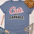 Women's funny woodworking graphic tee shirt for female woodworkers, makers, and DIY builders — Sawdust & Ponytails. Blue cotton tee with "Cute BUT CAPABLE." in pink and black.