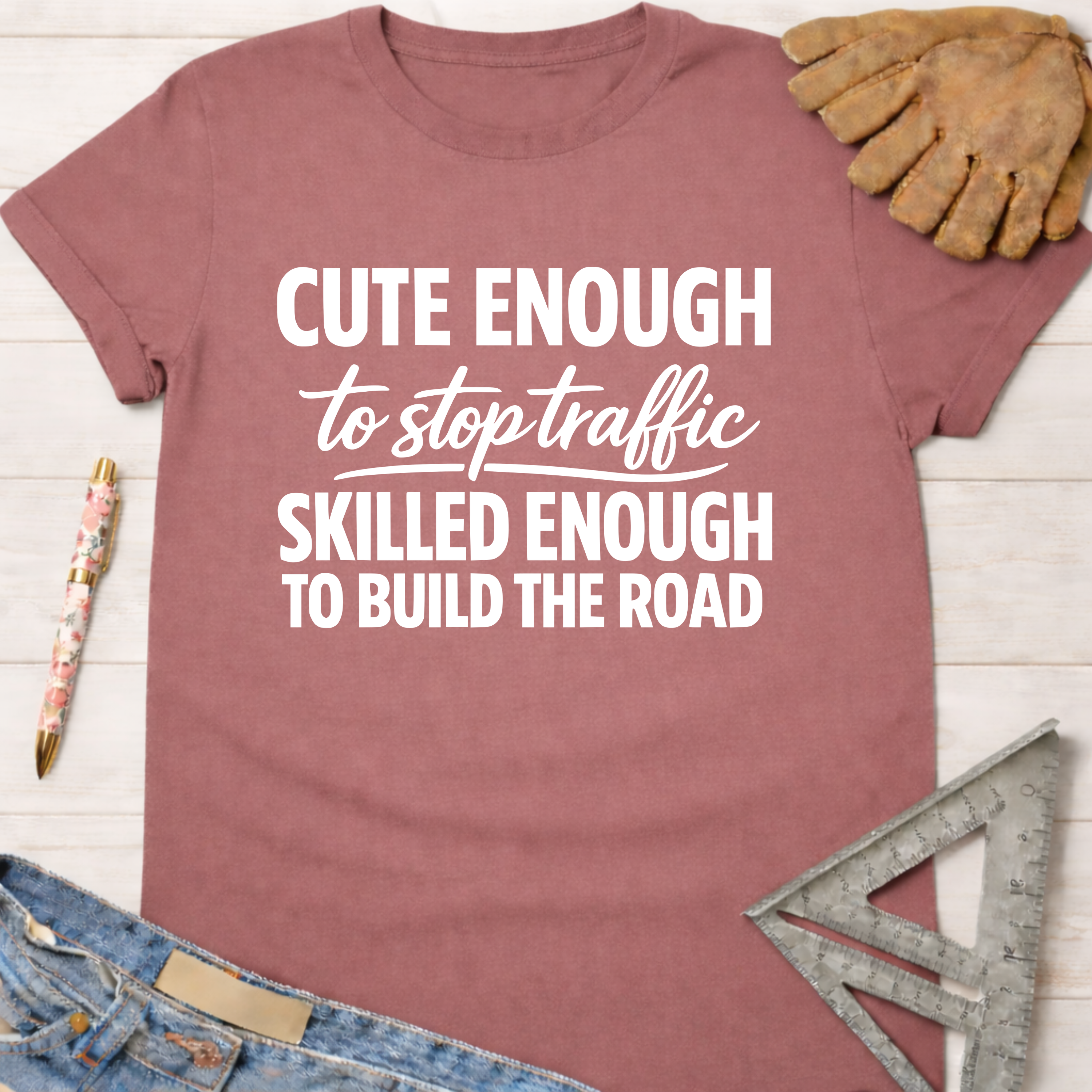 Women's funny woodworking graphic tee shirt for female woodworkers, makers, and DIY builders — Sawdust & Ponytails. Mauve t-shirt with "Cute Enough To Stop Traffic Skilled Enough To Build The Road" in white text.