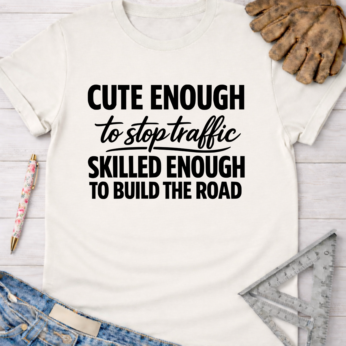 Women's funny woodworking graphic tee shirt for female woodworkers, makers, and DIY builders — Sawdust & Ponytails. White cotton tee with "Cute Enough To Stop Traffic Skilled Enough To Build The Road" in black text.