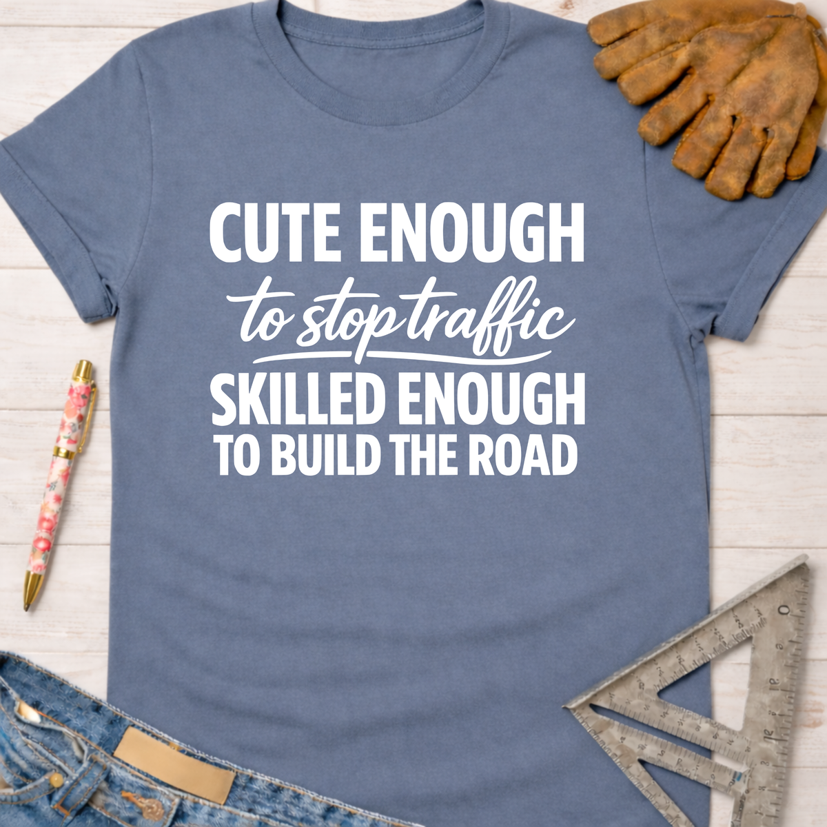 Women's funny woodworking graphic tee shirt for female woodworkers, makers, and DIY builders — Sawdust & Ponytails. Blue cotton t-shirt with "Cute Enough To Stop Traffic Skilled Enough To Build The Road" in white text.