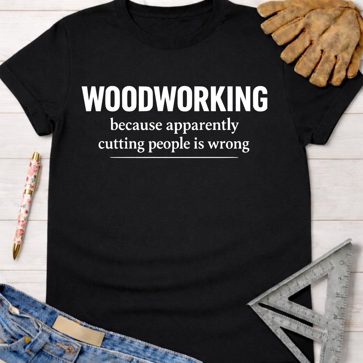 Women's black cotton "Woodworking because apparently cutting people is wrong" graphic tee, with work glove, pen, and ruler.