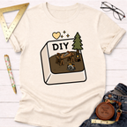Women's funny woodworking graphic tee shirt for female woodworkers, makers, and DIY builders — Sawdust & Ponytails. Cream t-shirt with a "DIY" computer key graphic featuring a workbench, saw, tree, and circular saw.