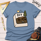 Women's funny woodworking graphic tee shirt for female woodworkers, makers, and DIY builders — Sawdust & Ponytails. Blue cotton tee with "DIY" button graphic featuring a workbench, saw, tree, and circular saw.