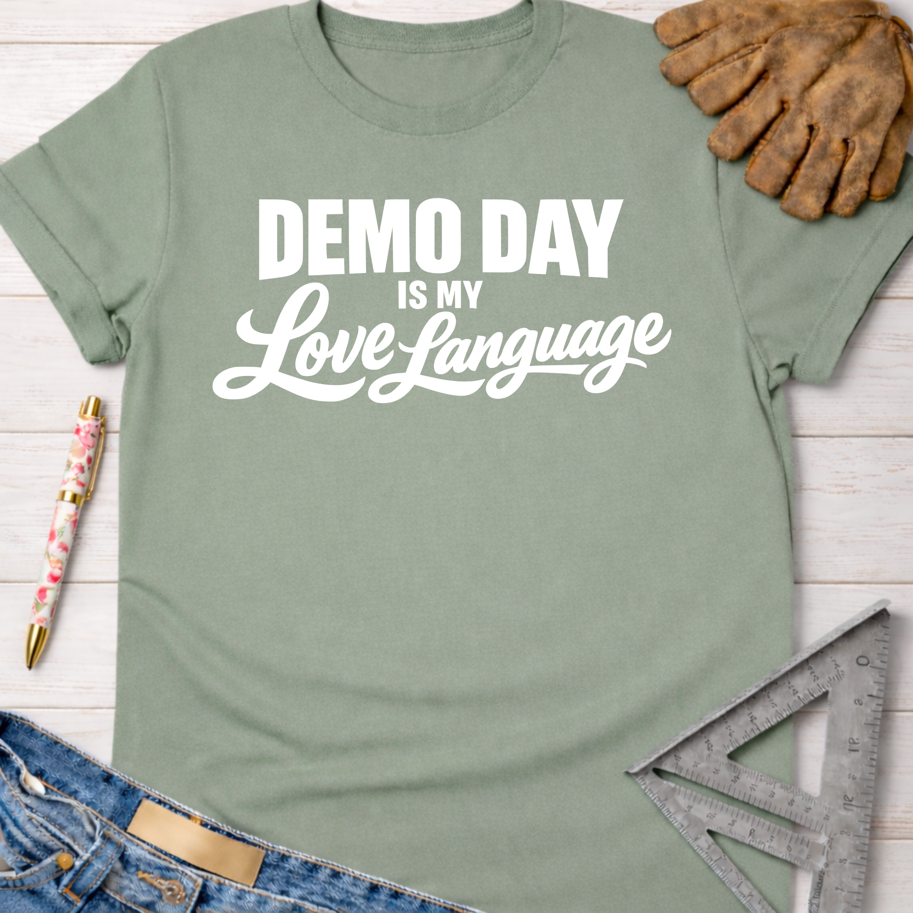 Women's funny woodworking graphic tee shirt for female woodworkers, makers, and DIY builders — Sawdust & Ponytails. Sage green cotton tee with "Demo Day is my Love Language" in white text.