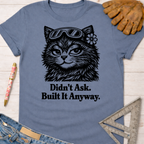 Women's funny woodworking graphic tee shirt for female woodworkers, makers, and DIY builders — Sawdust & Ponytails. Blue crew neck t-shirt with a black graphic of a cat wearing goggles and a flower, text reads "Didn't Ask. Built It Anyway.