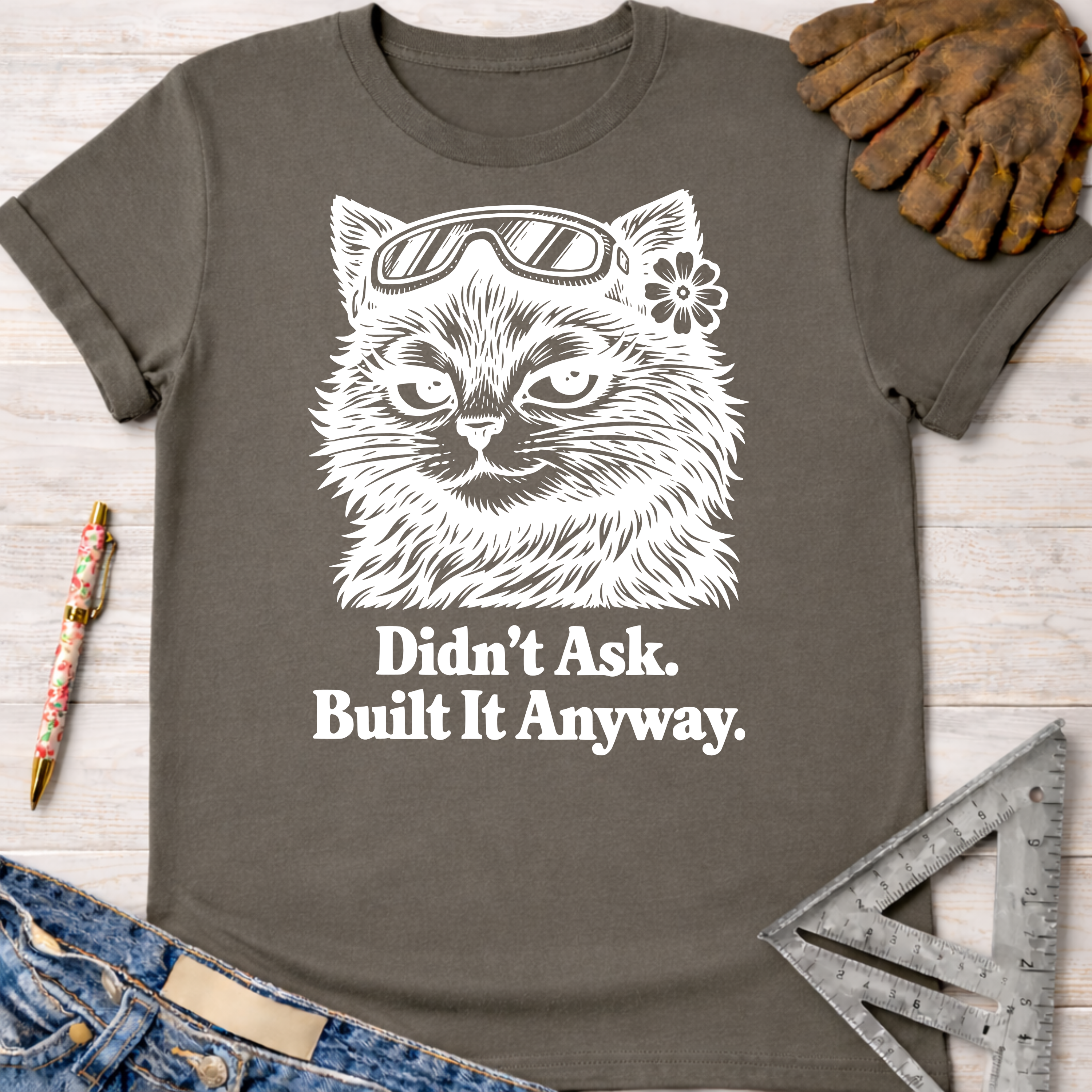 Women's funny woodworking graphic tee shirt for female woodworkers, makers, and DIY builders — Sawdust & Ponytails. Charcoal gray cotton tee with white graphic of a cat in goggles and "Didn't Ask. Built It Anyway.