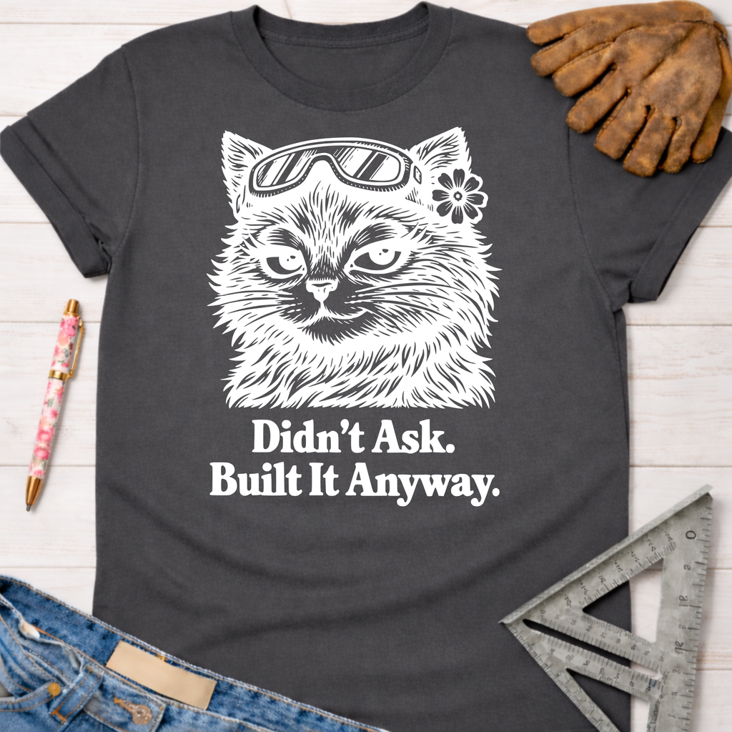 Charcoal gray "Didn't Ask. Built It Anyway." tee with a sassy cat in goggles. Women's funny woodworking graphic tee shirt for female woodworkers, makers, and DIY builders — Sawdust & Ponytails.