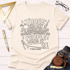 Cream t-shirt with "Those who say it cannot be done shouldn't interrupt the people doing it. I work alone" text and tools.