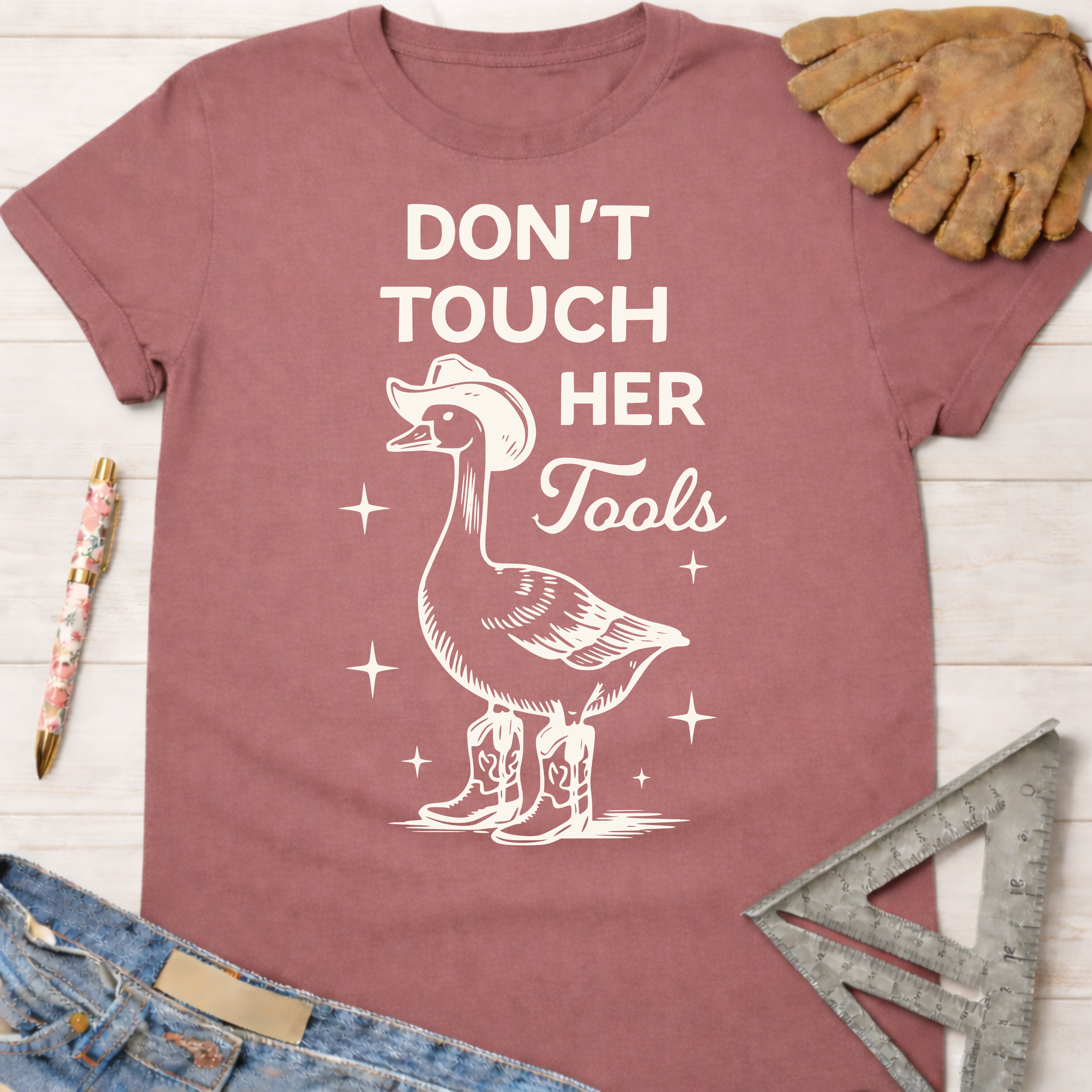 Mauve cotton t-shirt with a goose in a cowboy hat and boots, "Don't Touch Her Tools" graphic. Women's funny woodworking graphic tee shirt for female woodworkers, makers, and DIY builders — Sawdust & Ponytails