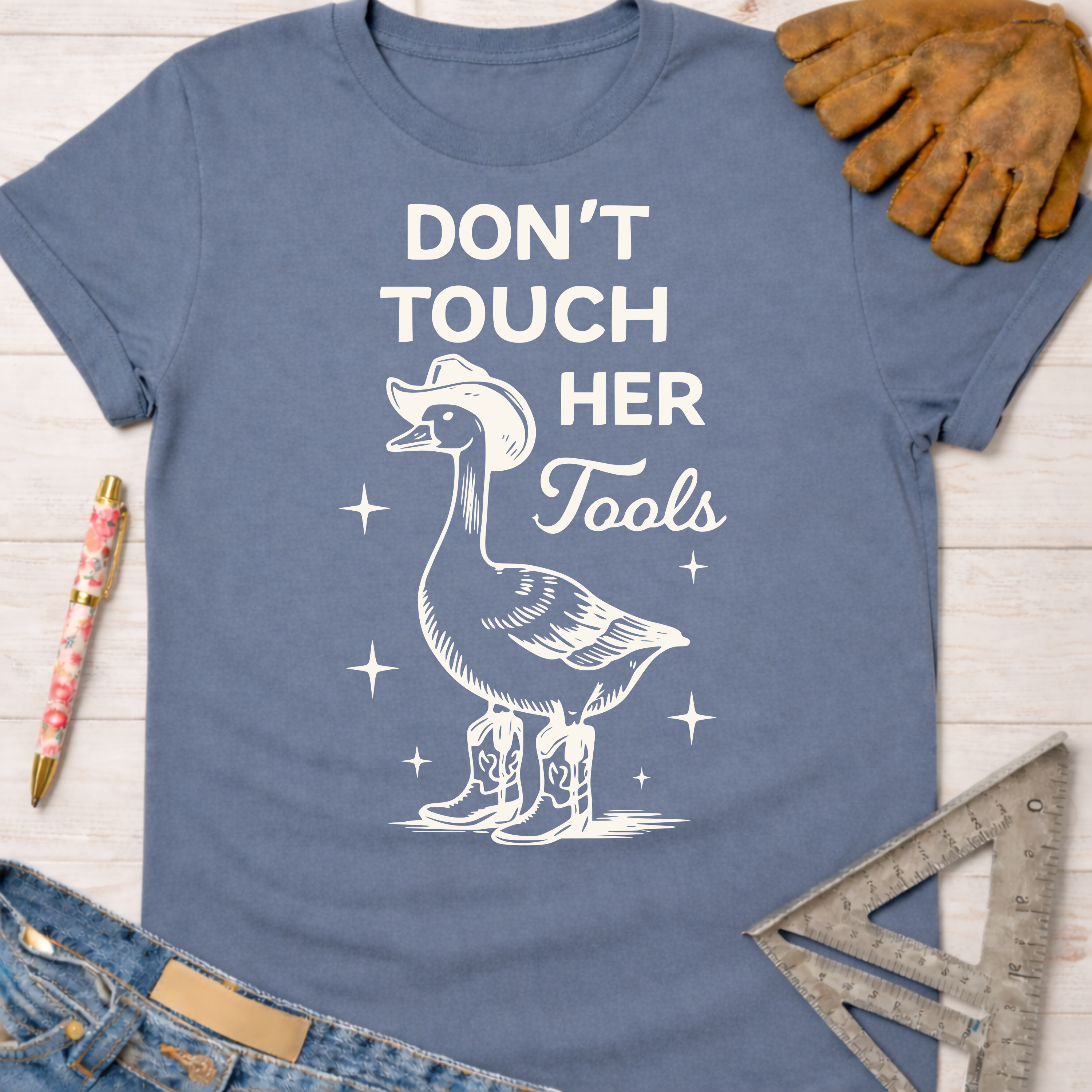 Women's funny woodworking graphic tee shirt for female woodworkers, makers, and DIY builders — Sawdust & Ponytails. Blue cotton tee with a goose in a cowboy hat and boots, "Don't Touch Her Tools" text.