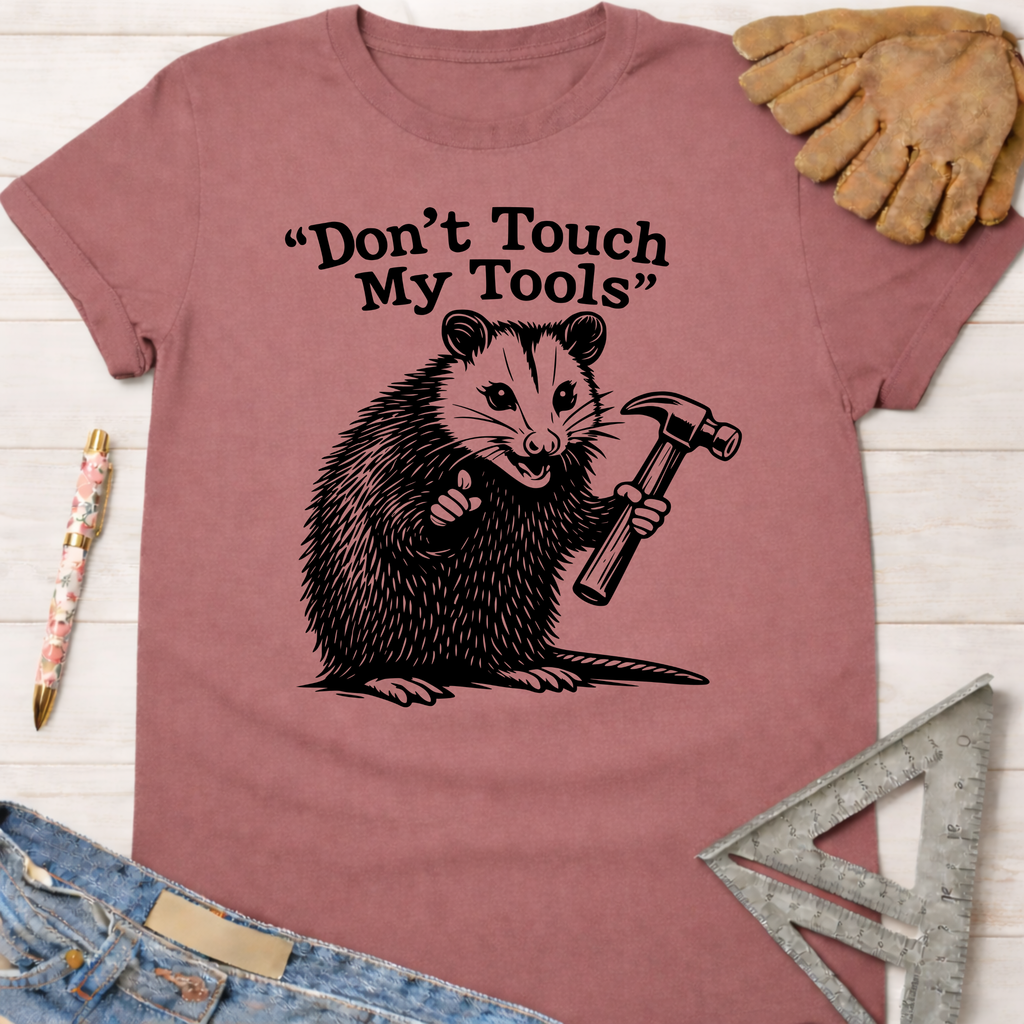 Women's funny woodworking graphic tee shirt for female woodworkers, makers, and DIY builders — Sawdust & Ponytails. Mauve cotton t-shirt with a possum holding a hammer and "Don't Touch My Tools" text.