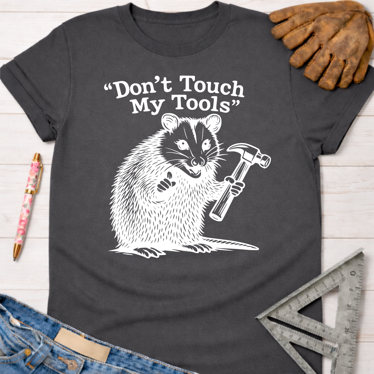 Women's funny woodworking graphic tee shirt for female woodworkers, makers, and DIY builders — Sawdust & Ponytails. Dark gray cotton tee with a white badger holding a hammer and "Don't Touch My Tools" text.