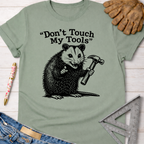 Sage green "Don't Touch My Tools" t-shirt with a possum holding a hammer. Women's funny woodworking graphic tee shirt for female woodworkers, makers, and DIY builders — Sawdust & Ponytails.
