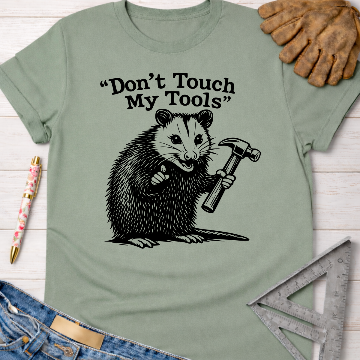 Sage green "Don't Touch My Tools" t-shirt with a possum holding a hammer. Women's funny woodworking graphic tee shirt for female woodworkers, makers, and DIY builders — Sawdust & Ponytails.