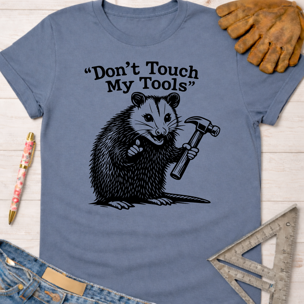 Women's funny woodworking graphic tee shirt for female woodworkers, makers, and DIY builders — Sawdust & Ponytails. Blue cotton tee with a possum holding a hammer and "Don't Touch My Tools" text.