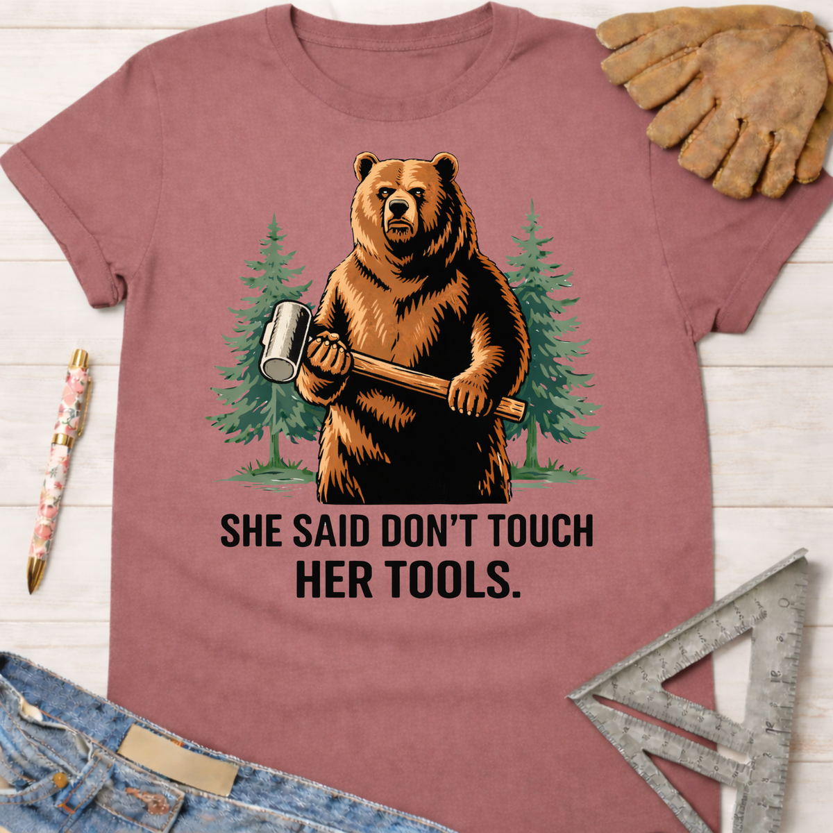Women's funny woodworking graphic tee shirt for female woodworkers, makers, and DIY builders — Sawdust & Ponytails. Mauve t-shirt with a bear holding a mallet and "SHE SAID DON'T TOUCH HER TOOLS" text.