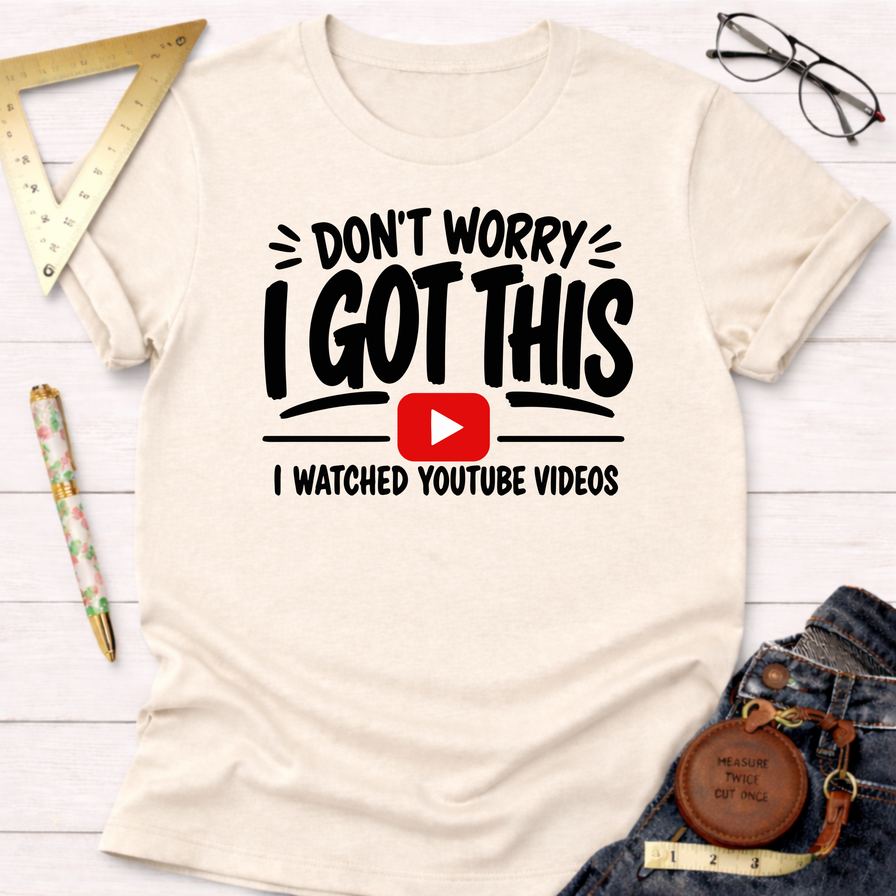 Cream t-shirt with "Don't Worry I Got This I Watched YouTube Videos" text and play button graphic.