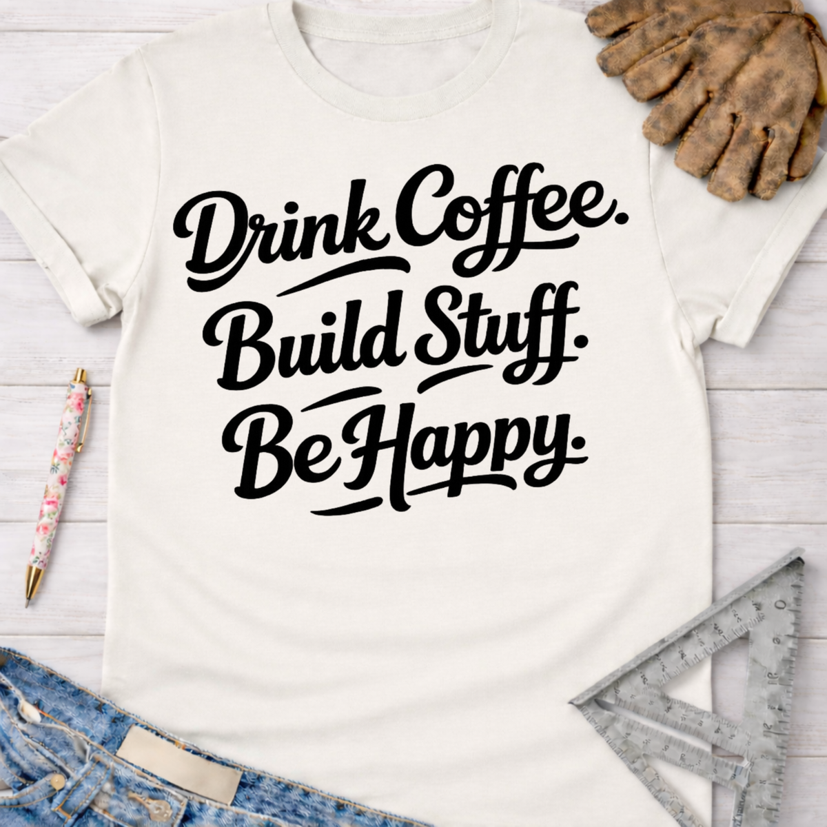 Women's funny woodworking graphic tee shirt for female woodworkers, makers, and DIY builders — Sawdust & Ponytails. Cream t-shirt with "Drink Coffee. Build Stuff. Be Happy." in black script.