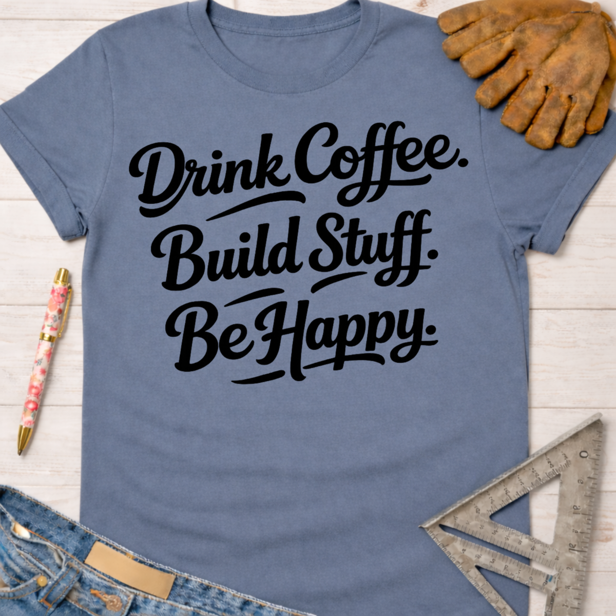 Women's funny woodworking graphic tee shirt for female woodworkers, makers, and DIY builders — Sawdust & Ponytails. Blue cotton t-shirt with "Drink Coffee. Build Stuff. Be Happy." in black script.