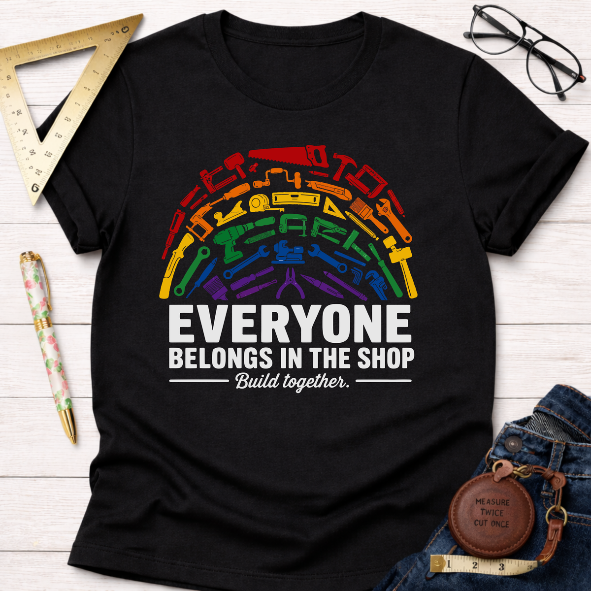 Black unisex cotton t-shirt with a rainbow arc of colorful tools and "Everyone Belongs In The Shop Build together." text.