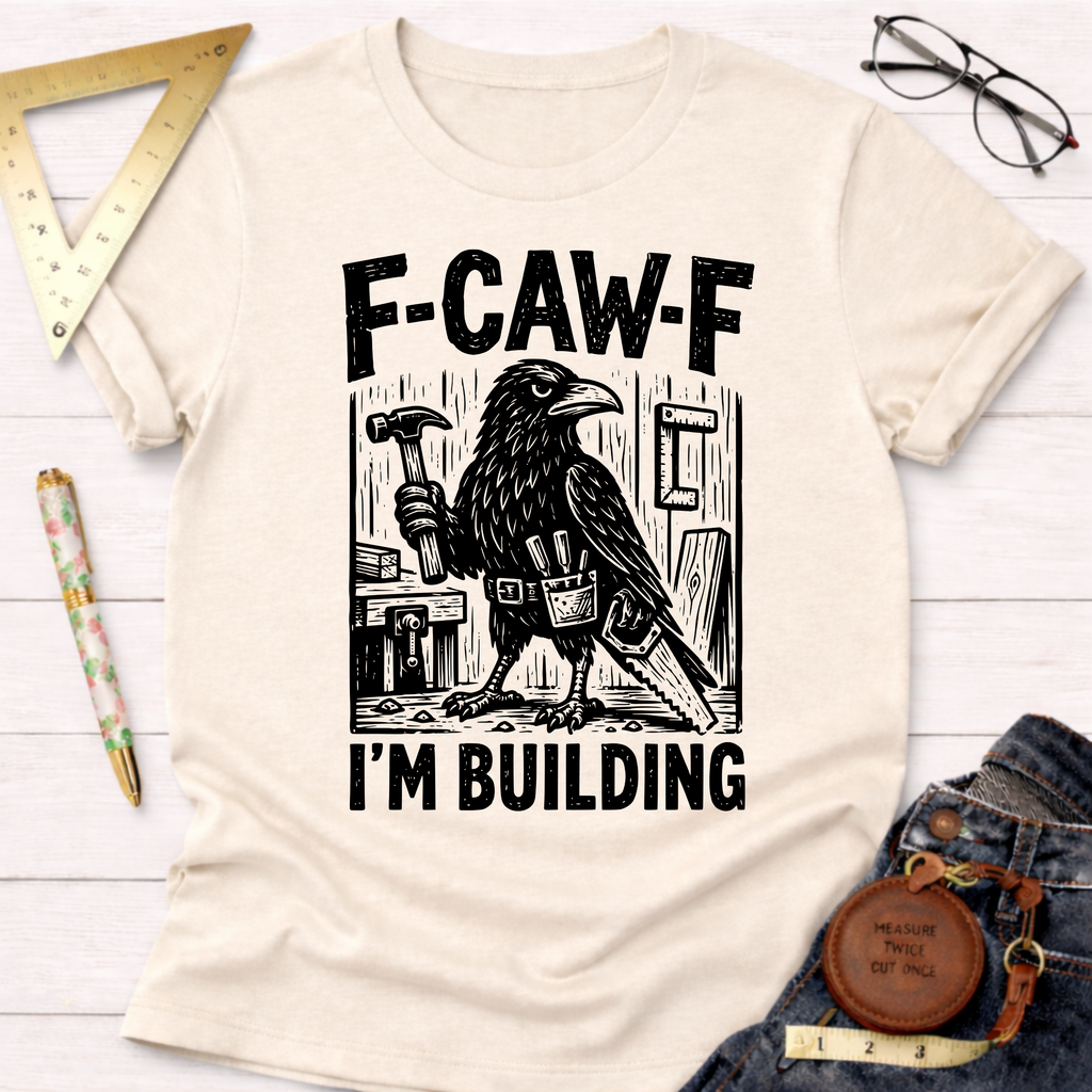 Women's funny woodworking graphic tee shirt for female woodworkers, makers, and DIY builders — Sawdust & Ponytails. Cream t-shirt with a black crow holding a hammer and "F-CAW-F I'M BUILDING" text.