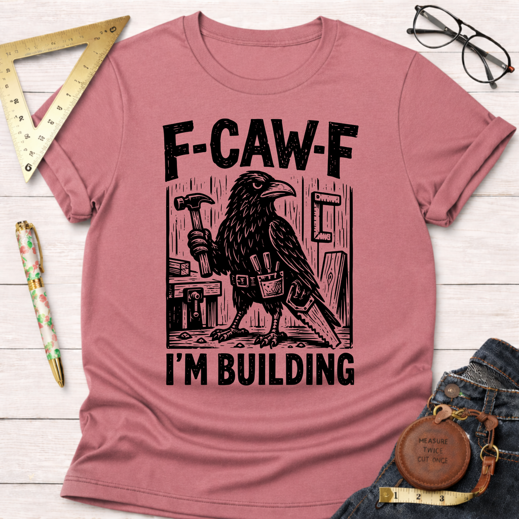 Women's funny woodworking graphic tee shirt for female woodworkers, makers, and DIY builders — Sawdust & Ponytails. Heather mauve cotton tee with a black crow holding a hammer and saw, text "F-CAW-F I'M BUILDING".