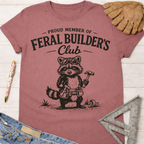 Women's funny woodworking graphic tee shirt for female woodworkers, makers, and DIY builders — Sawdust & Ponytails. Mauve t-shirt with a raccoon in sunglasses and tool belt, holding a hammer.