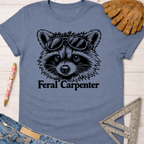 Women's funny woodworking graphic tee shirt for female woodworkers, makers, and DIY builders — Sawdust & Ponytails. Blue Feral Carpenter t-shirt with a raccoon wearing sunglasses.