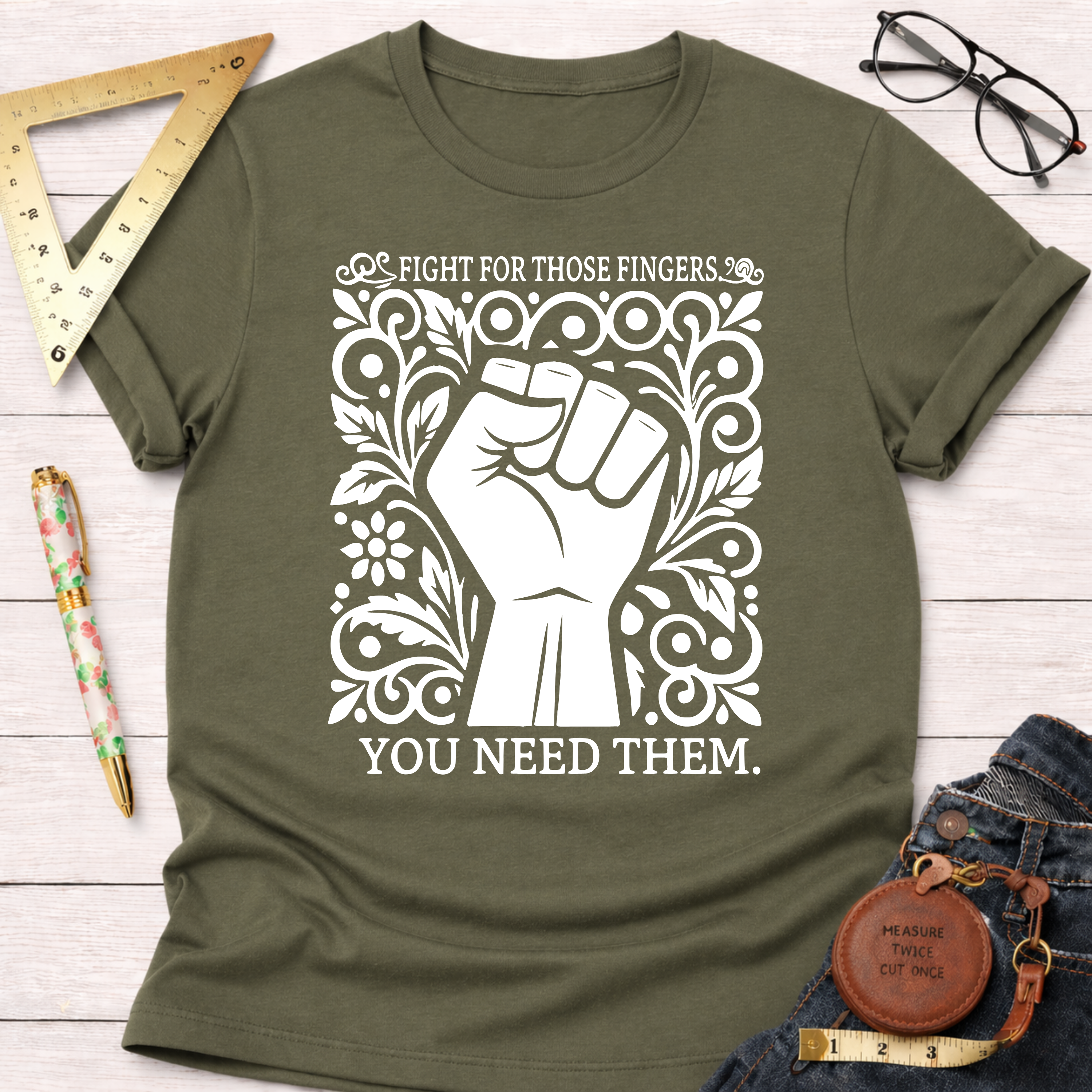 Olive green cotton t-shirt with a white graphic of a raised fist surrounded by ornate floral designs and text.