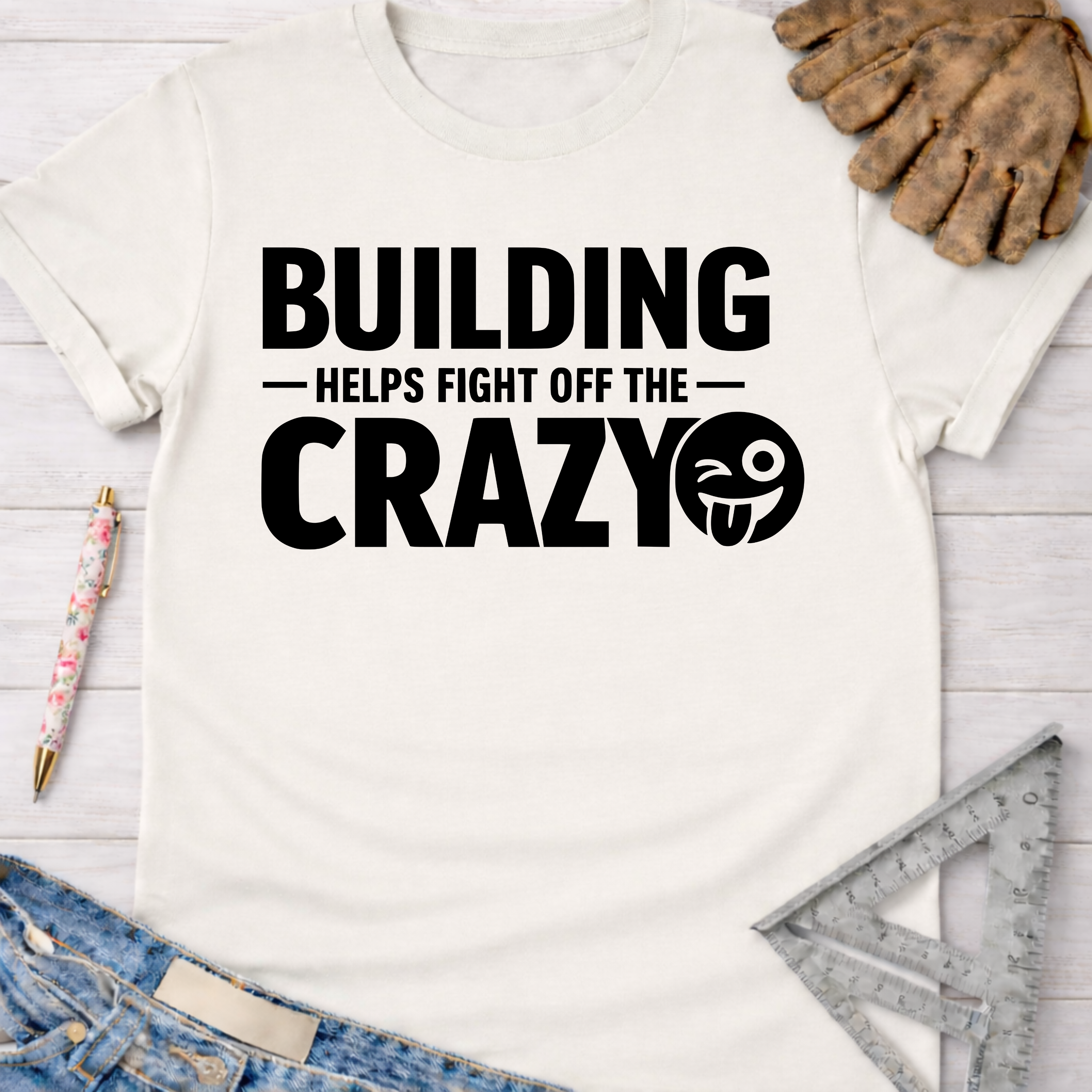Women's funny woodworking graphic tee shirt for female woodworkers, makers, and DIY builders — Sawdust & Ponytails. White cotton tee with "BUILDING HELPS FIGHT OFF THE CRAZY" text and winking emoji.