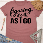 Women's funny woodworking graphic tee shirt for female woodworkers, makers, and DIY builders — Sawdust & Ponytails. Mauve cotton tee with "Figuring It Out As I Go" text.