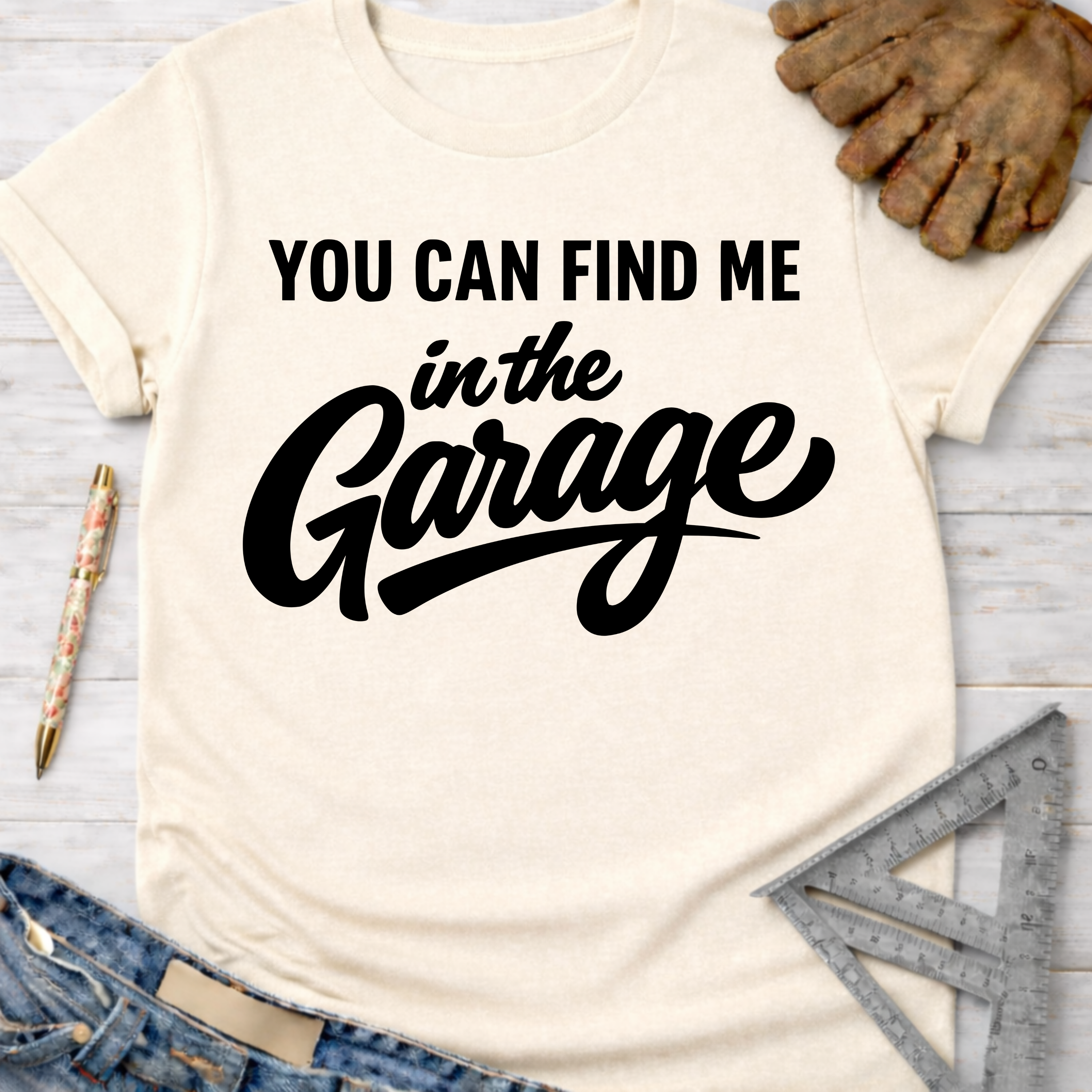 Women's funny woodworking graphic tee shirt for female woodworkers, makers, and DIY builders — Sawdust & Ponytails. Cream short-sleeve t-shirt with "YOU CAN FIND ME in the Garage" in black text.